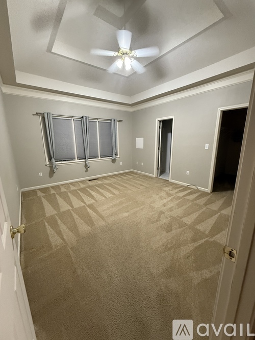 A room with a carpeted floor and a ceiling fan.