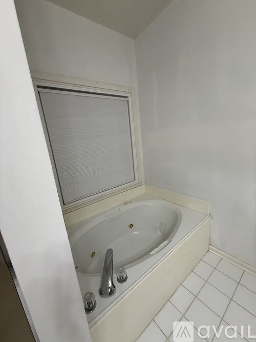 A white bathroom with a tub and a window.