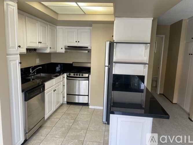 A kitchen with white cabinets and black countertops.