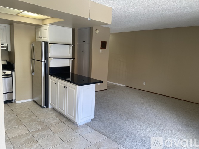 A kitchen with a refrigerator, oven, and cabinets.