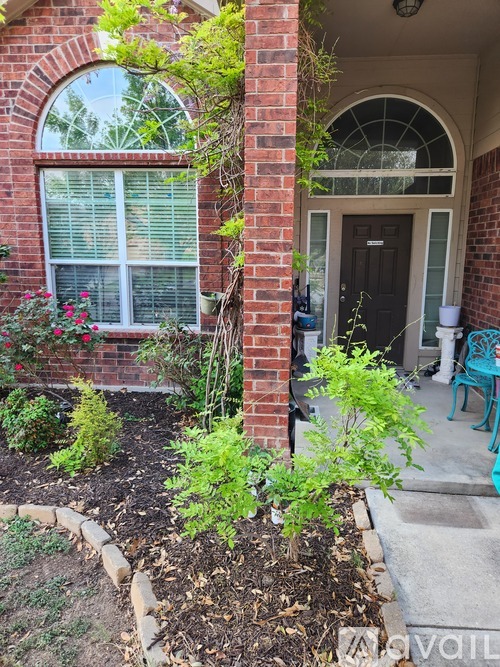 A small garden in front of a house with a brick pillar.