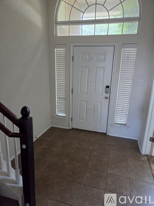 A hallway with a white door and a window above it.