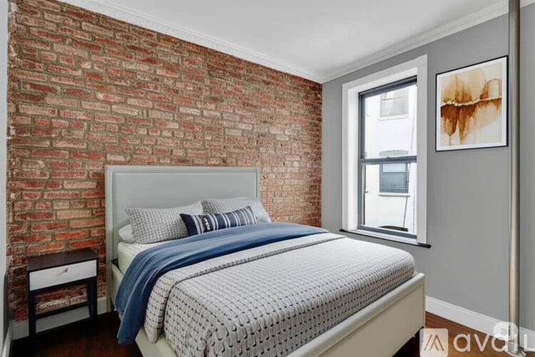 A bedroom with a brick wall and a bed with a blue and white comforter.