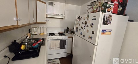 A kitchen with a white refrigerator covered in magnets and a stove with a pot on it.