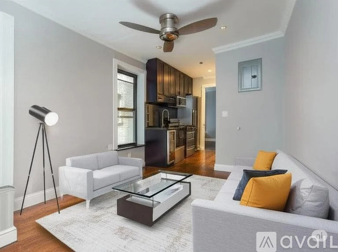 A modern living room with a white sofa, a glass coffee table, and a ceiling fan.