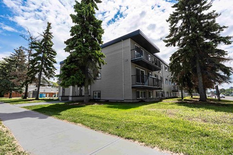 A modern apartment building with a paved walkway in front.