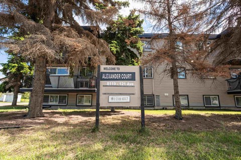 A sign welcoming people to Alexander Court stands in front of a building.
