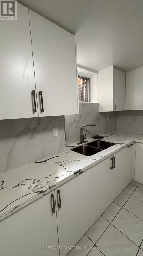 A kitchen with white cabinets and a marble countertop.