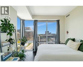 A bedroom with a large bed and a view of the city through the window.