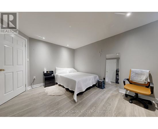 A bedroom with a bed, chair, and suitcase.