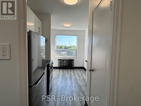 A kitchen with a refrigerator and a door leading to a hallway.