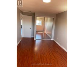 A room with wooden floors and a sliding glass door leading to a balcony.