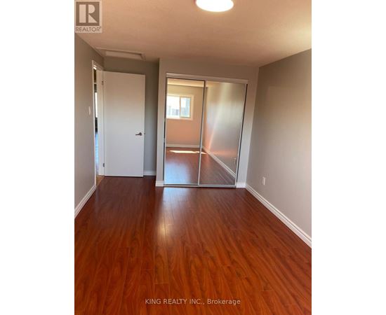 A room with wooden floors and a sliding glass door leading to a balcony.