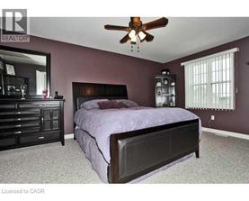 A bedroom with a bed, dresser, and ceiling fan.