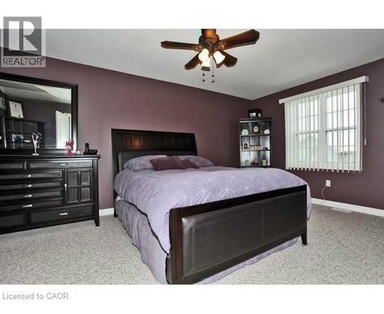 A bedroom with a bed, dresser, and ceiling fan.