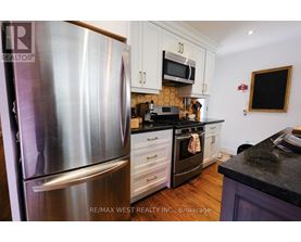 A kitchen with a stainless steel refrigerator and a black countertop.