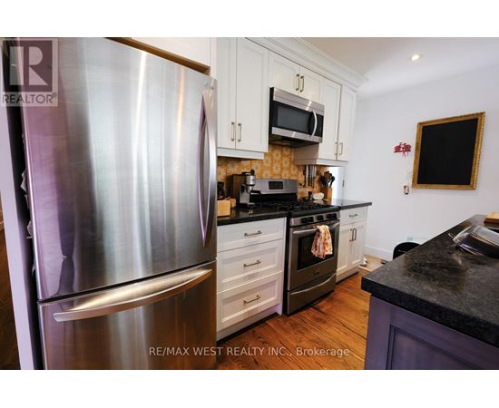 A kitchen with a stainless steel refrigerator and a black countertop.