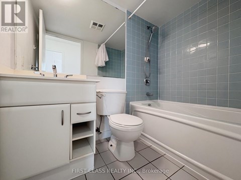 A white toilet sits in a bathroom with blue tiles.
