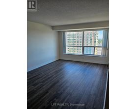 A room with wooden flooring and a large window overlooking a cityscape.