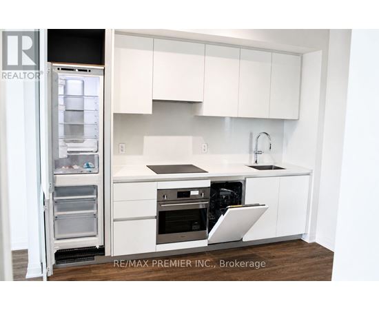 A white kitchen with a refrigerator and sink.