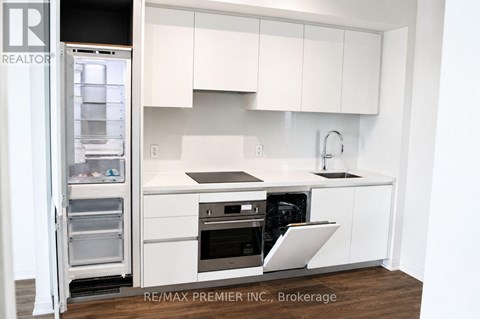 A white kitchen with a refrigerator and sink.
