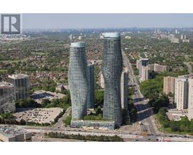 Two tall buildings are situated in a city with a highway running in between them.