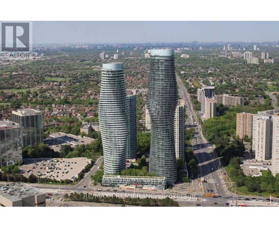 Two tall buildings are situated in a city with a highway running in between them.