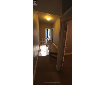 A hallway with a light on and a door at the end.