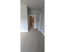 A room with a carpeted floor and a doorway leading to another room.