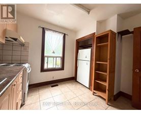 A kitchen with a refrigerator, a window, and a wooden cabinet.