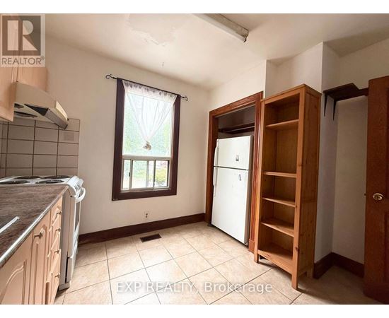 A kitchen with a refrigerator, a window, and a wooden cabinet.