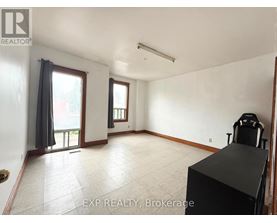 A room with a black desk and a window with curtains.