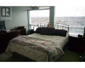 A bedroom with a bed, desk, and window overlooking the ocean.