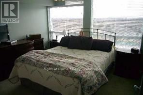 A bedroom with a bed, desk, and window overlooking the ocean.