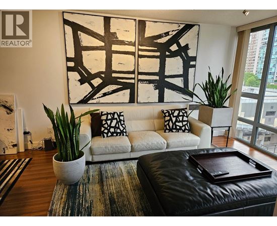A living room with a white couch, a large abstract painting, and a coffee table with a tray on it.