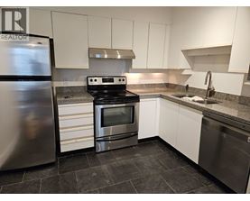 A kitchen with a stainless steel refrigerator, oven, and sink.