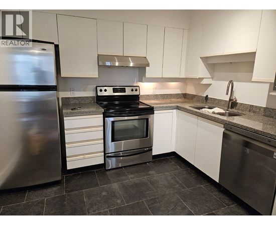 A kitchen with a stainless steel refrigerator, oven, and sink.