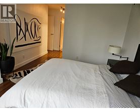 A bedroom with a large bed and a painting on the wall.
