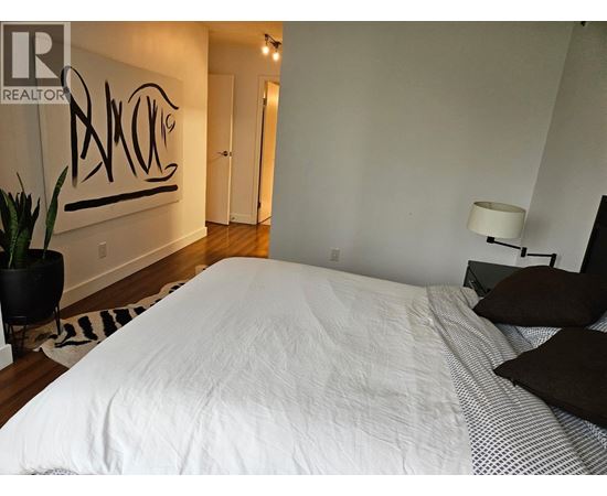 A bedroom with a large bed and a painting on the wall.