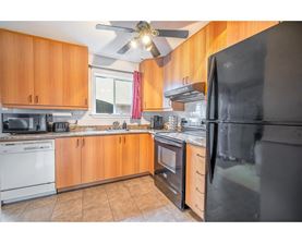 A kitchen with wooden cabinets and a black refrigerator.