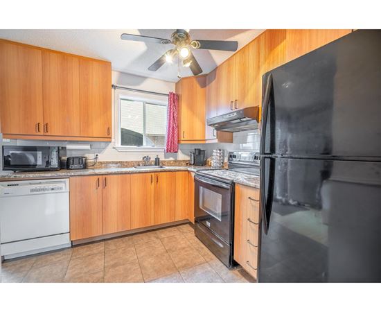 A kitchen with wooden cabinets and a black refrigerator.