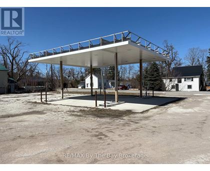A large white carport with a metal roof is situated in a parking lot.