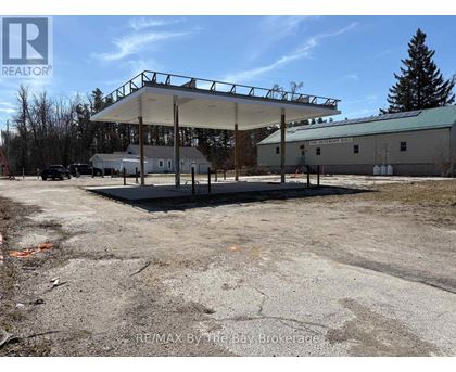 A large, empty parking lot with a gas station and a building in the background.
