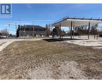A large, empty field with a building and a carport in the background.