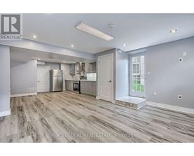 A spacious kitchen with wood flooring and white walls.