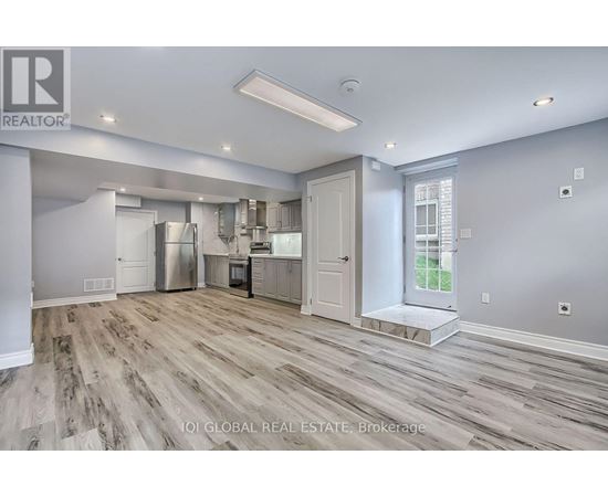 A spacious kitchen with wood flooring and white walls.
