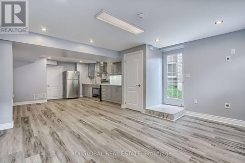 A spacious kitchen with wood flooring and white walls.