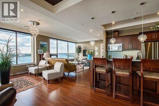 A living room with a large window and a dining area with chairs.