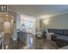 A well-lit, spacious kitchen and living room with hardwood floors and modern furnishings.