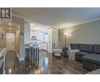 A well-lit, spacious kitchen and living room with hardwood floors and modern furnishings.